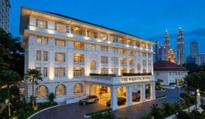 Exterior view of the historic Majestic Hotel in Kuala Lumpur at dusk, featuring its grand white colonial-style architecture.